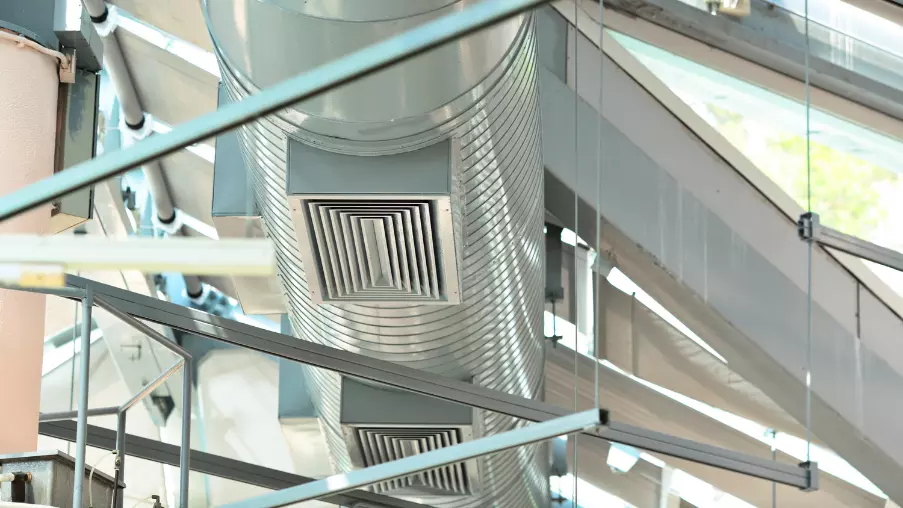 Système de ventilation moderne dans un bâtiment. Gros plan sur des conduits métalliques cylindriques et grilles d'aération.