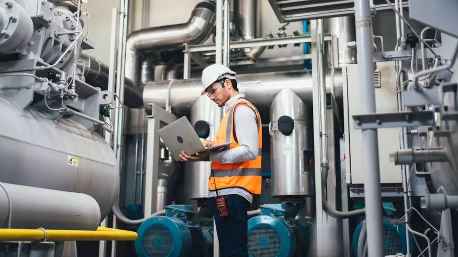 Un technicien fait un diagnostic énergétique sur son ordinateur dans un site industriel