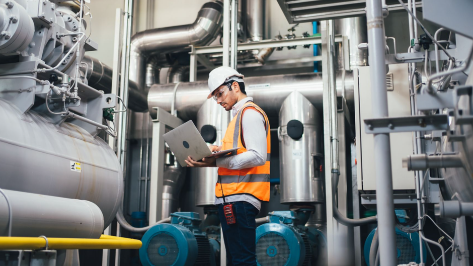 Un technicien fait un diagnostic énergétique sur son ordinateur dans un site industriel