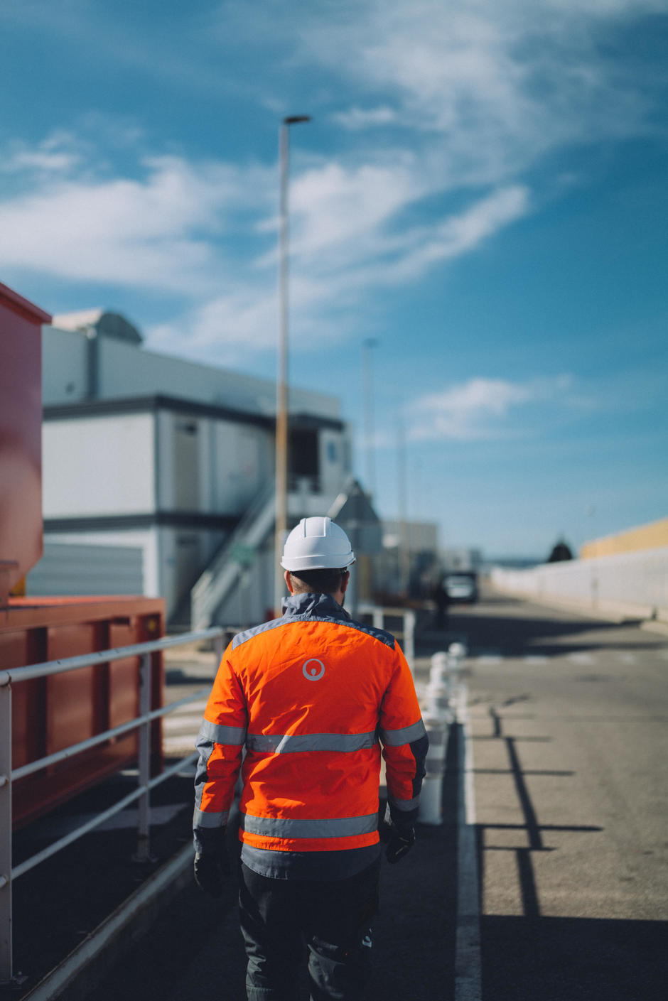 Un technicien Veolia marche avec des équipements de sécurité vers un site industriel