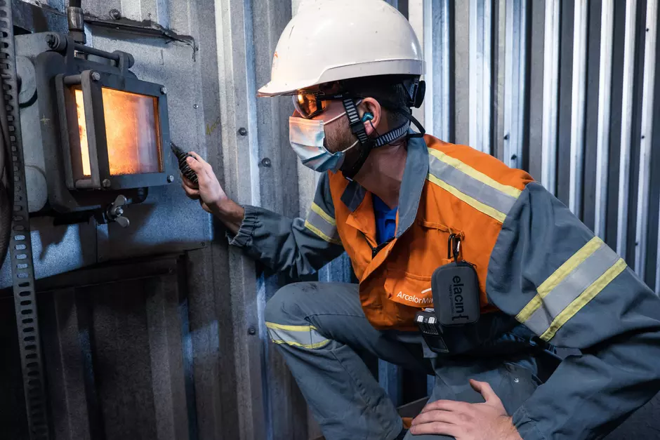 Un technicien équipé avec un casque et un masque effectue une prestation industrielle sur une chaudière
